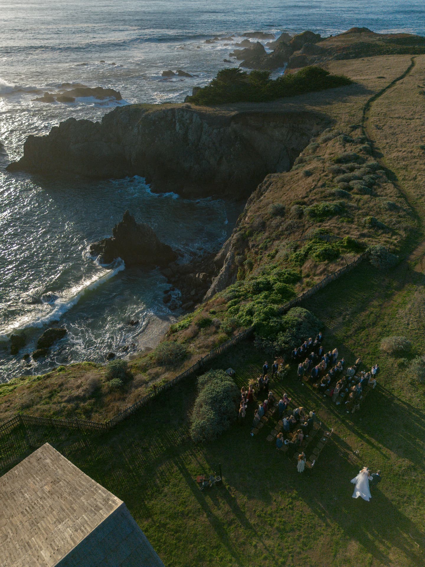 Aerial view of a wedding ceremony on a coastal bluff overlooking the Pacific Ocean